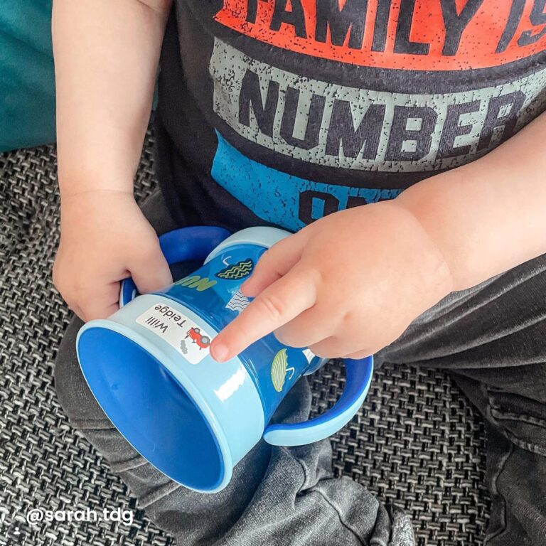 Klein kind plakt naamsticker op drinkfles