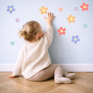 Daisy (meerkleurig) muurstickers worden door een kind op de muur geplakt