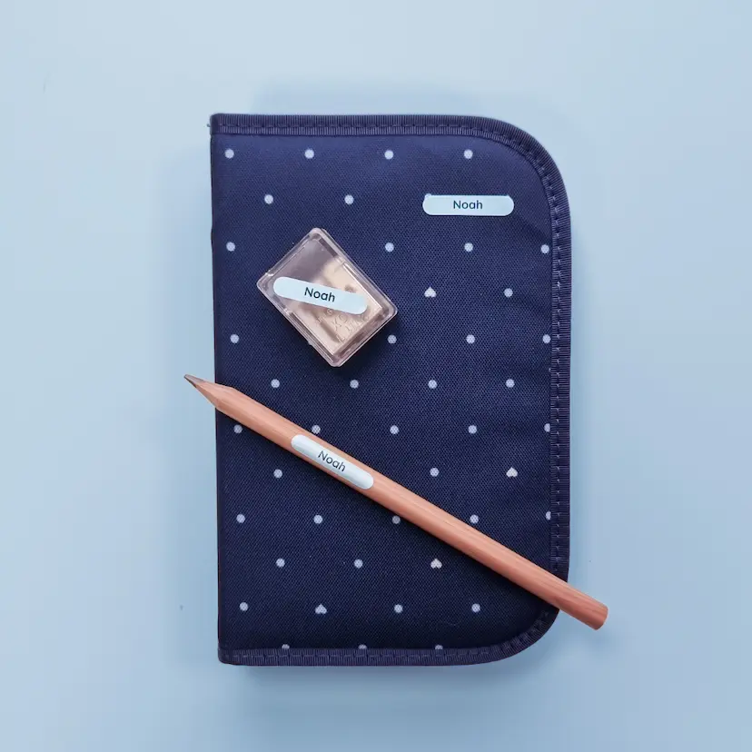 Naamlabels op een etui, potlood en puntenslijper.