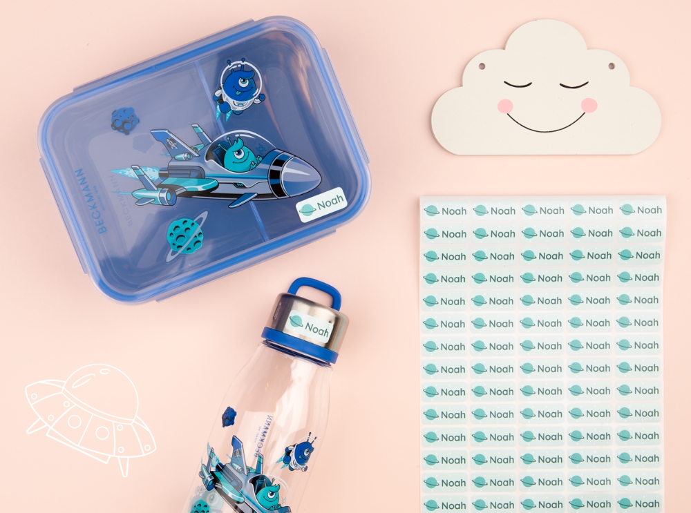 Blauwe lunchbox, waterfles en naamstickers met een ruimtethema.