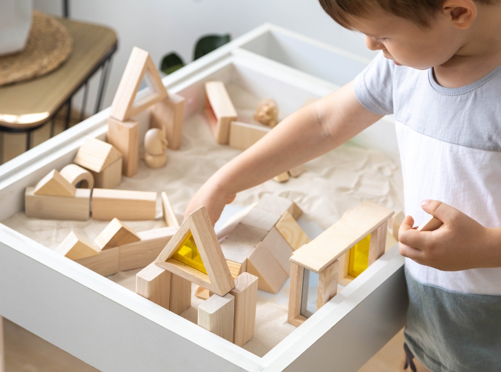 Kind speelt met houten bouwblokken aan een sensorische speeltafel