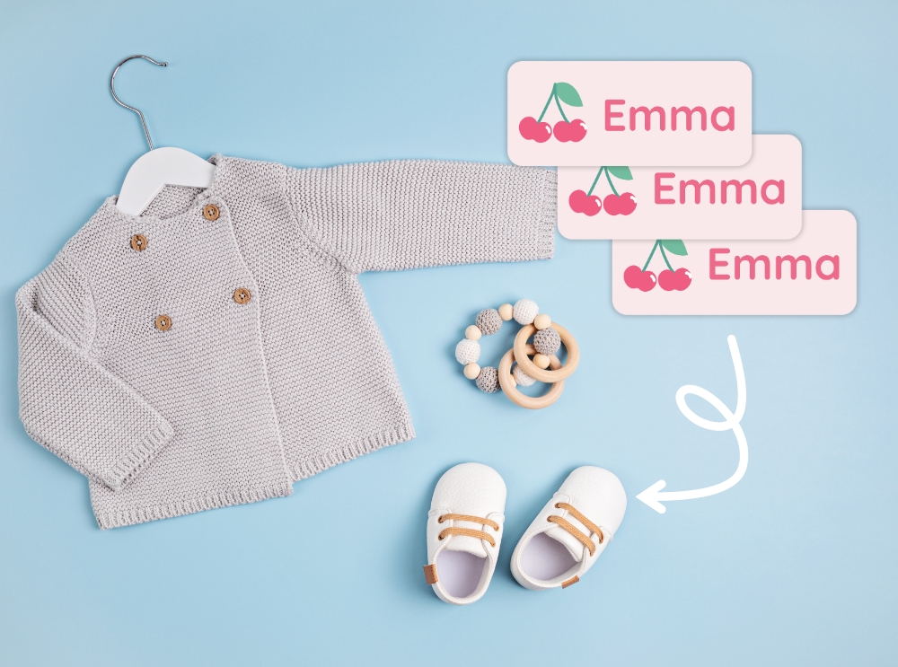 Extra kleding voor de kinderopvang: wat neem je mee en hoe blijf je georganiseerd? 2 Babykleertjes en schoentjes met roze naamstickers met kersjes en de naam emma