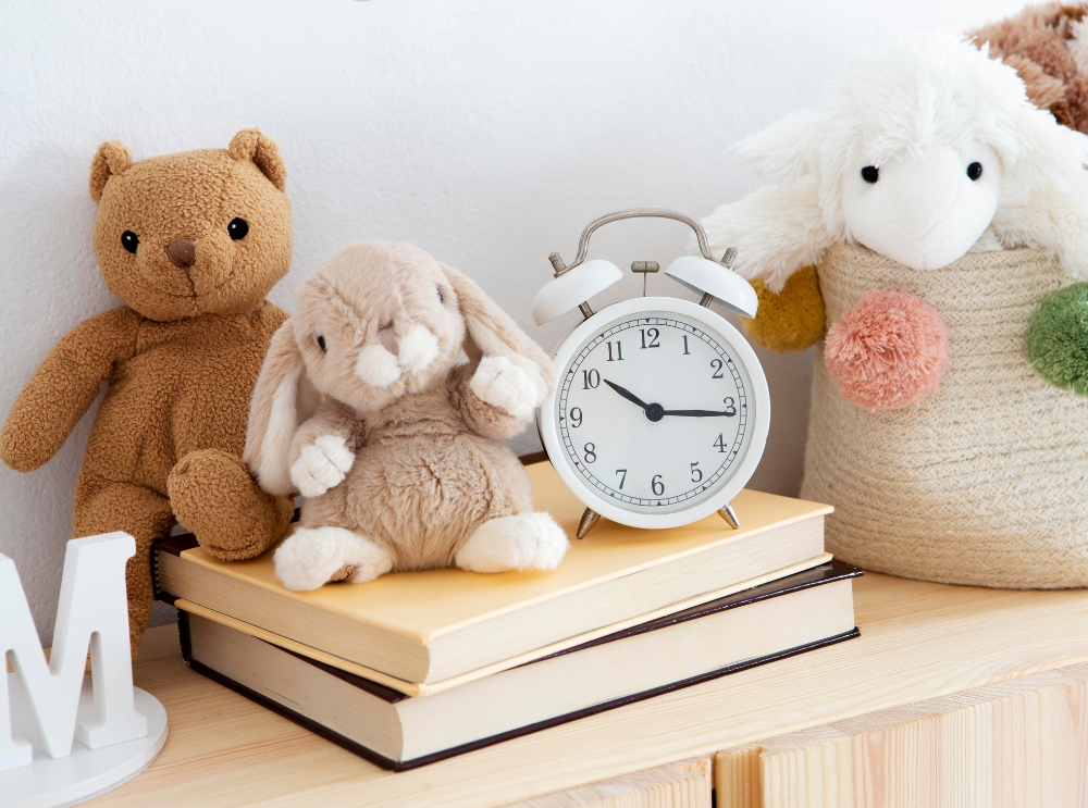 Knuffels en een witte wekker bovenop boeken in een knusse kinderkamer