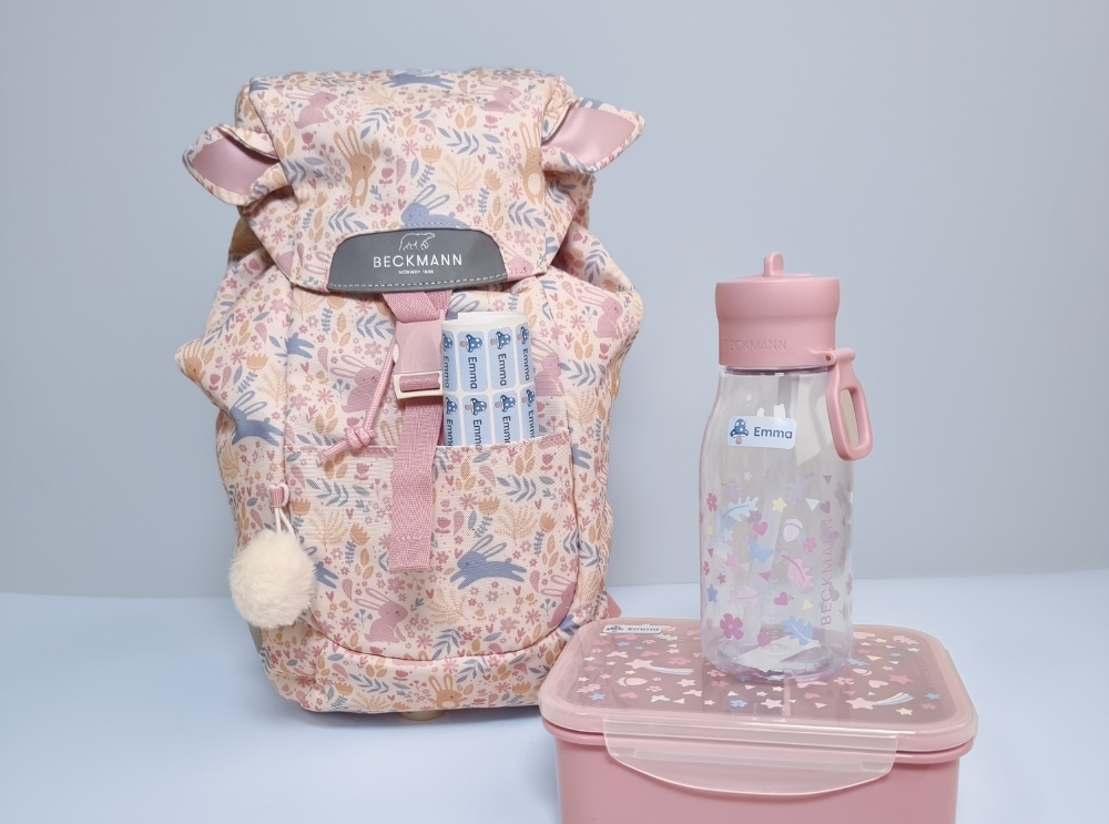 Matching floral backpack, water bottle, and lunchbox labeled with personalized name stickers for school or daycare