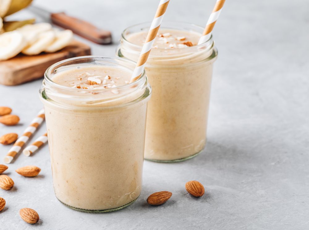 Banaan- en amandelsmoothie in een doorzichtig glas met een bruin rietje