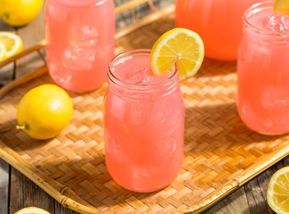 Kindvriendelijke roze limonade in een mason jar met ijsblokjes en een schijfje citroen