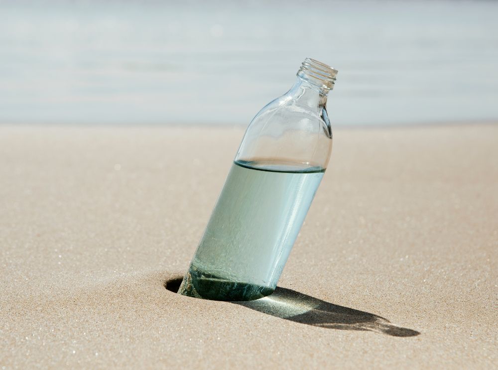 Drinkfles staand in het zand op het strand.