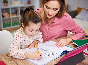 Mother helping her young daughter with homework, learning together at the table
