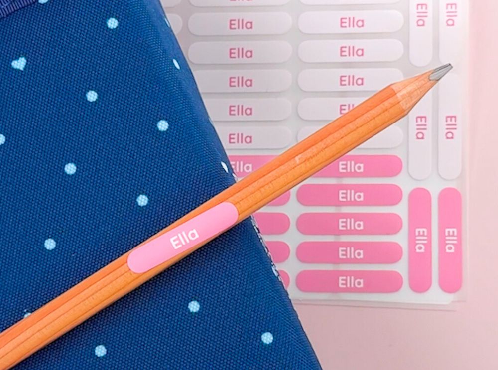 Roze potloodlabel met de naam ella, op een potlood geplaatst naast een bijpassend stickervel