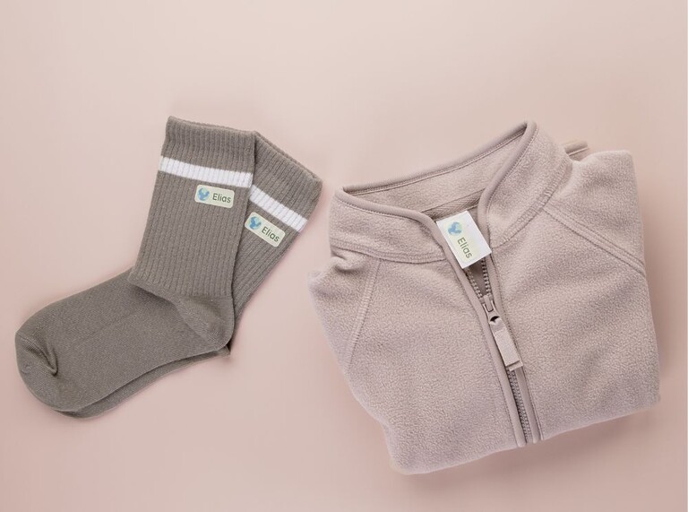 Folded jacket and socks labeled with personalized name labels