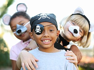 Children dressed in fun pirate and animal costumes smiling together at a birthday party.