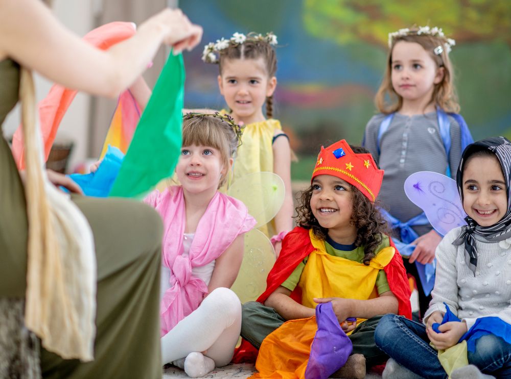 Kinderen in kleurrijke kostuums en kroontjes die samen een activiteit doen op een verjaardagsfeestje.