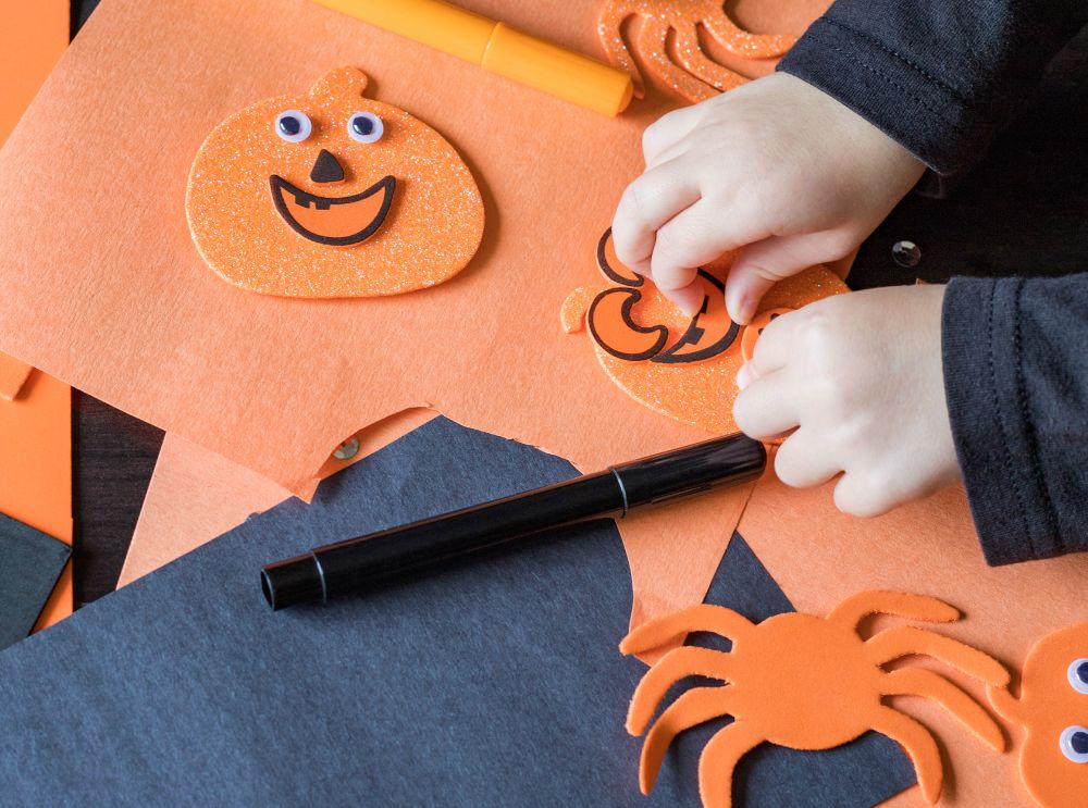 Kind dat pompoenknutsels maakt met oranje en zwart papier