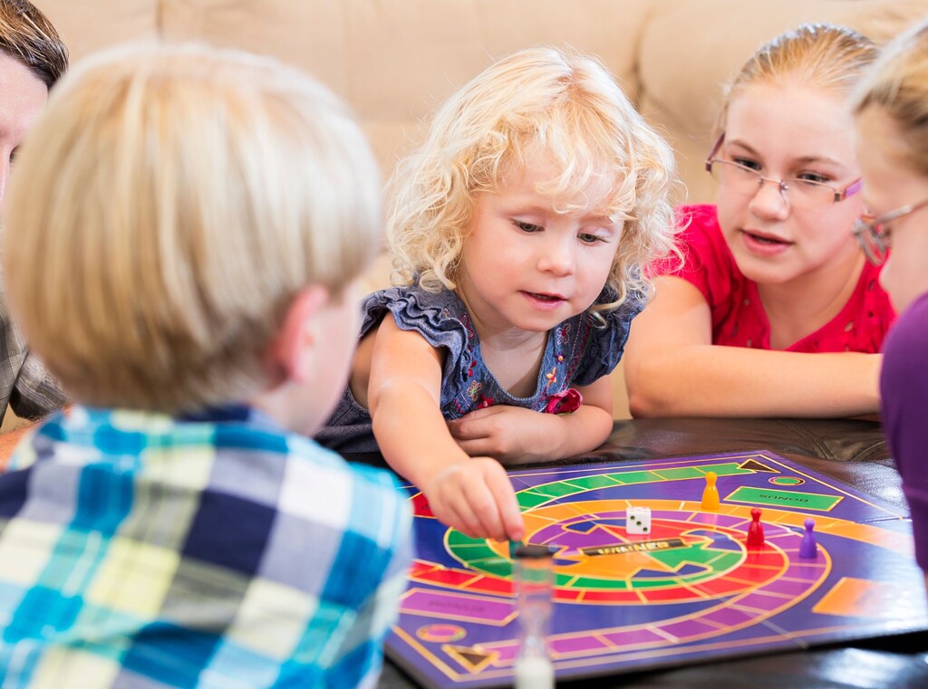 Kids gathered around a board game, taking turns and having fun together.