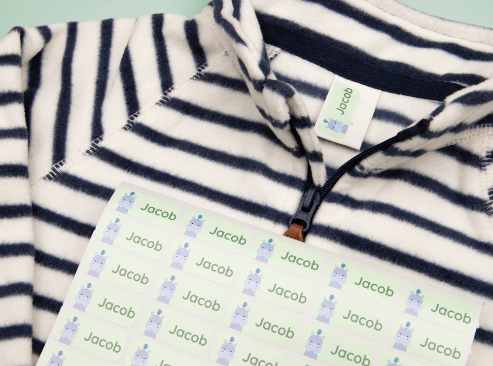 Vellen met groene naamstickers met een nijlpaardje, geplaatst op een gestreept hemd.