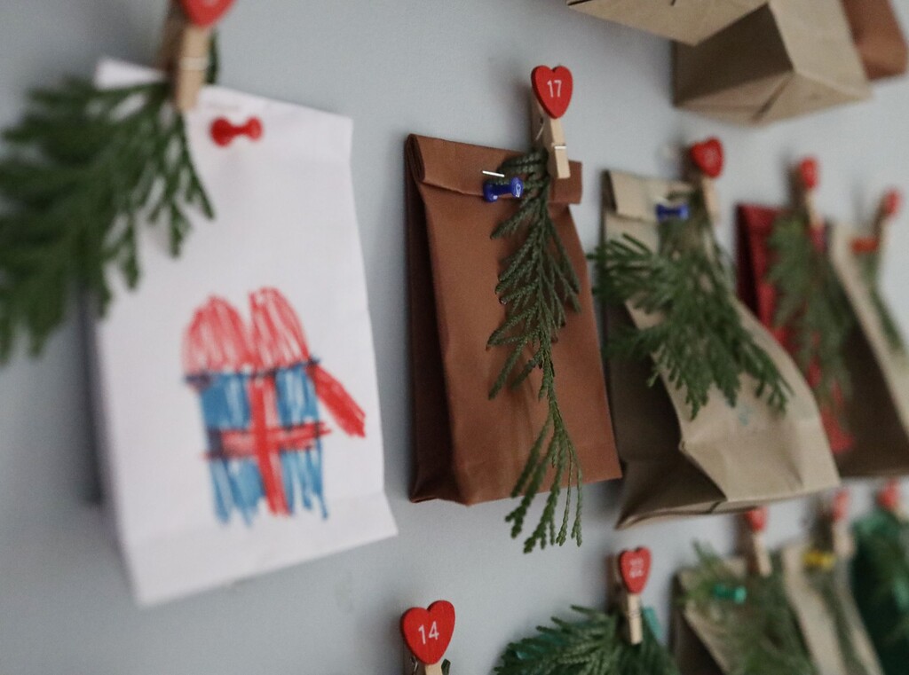 Close-up van zelfgemaakte adventszakjes aan de muur, versierd met tekeningen en dennentakjes.