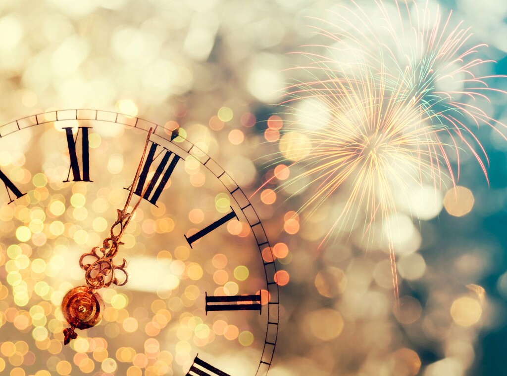 Oud en nieuw met kinderen: leuke ideeën voor een avond om nooit te vergeten 2 Klok vlak voor middernacht met vuurwerk op de achtergrond.