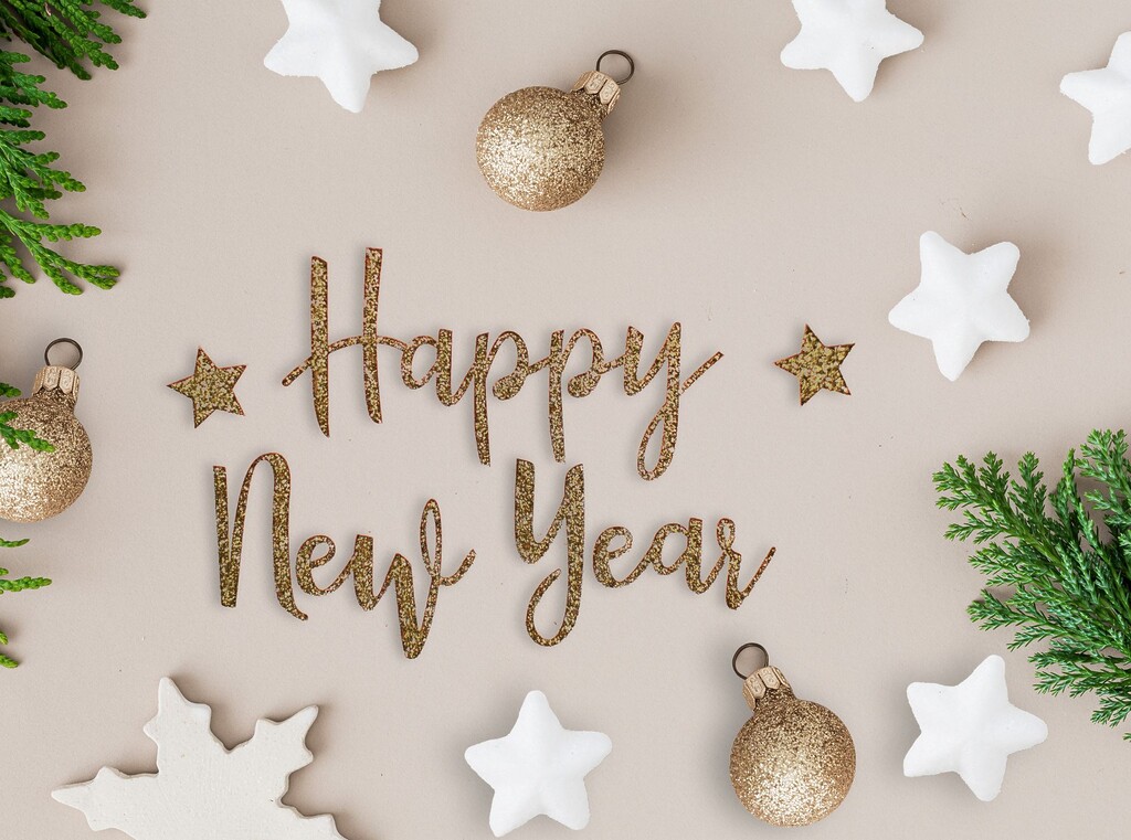 “Happy New Year” gold lettering surrounded by white stars and festive decorations