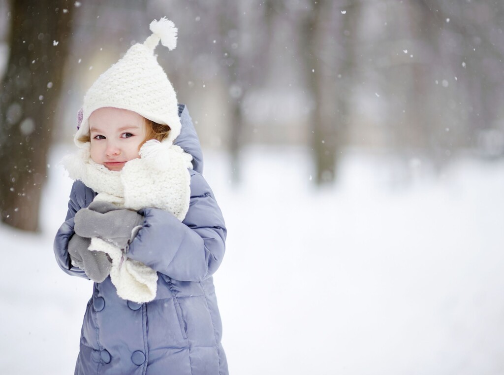 Gezond blijven tijdens het koude seizoen: zo ondersteun je het immuunsysteem van je kind 1 Peuter warm aangekleed in winterkleding, staand in de sneeuw.