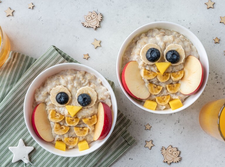 Cute owl-shaped oatmeal bowls decorated with fruit for a kid-friendly breakfast.