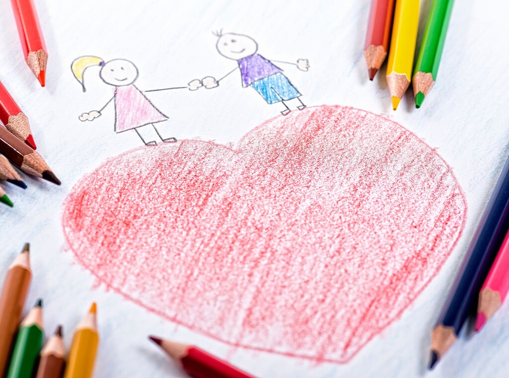 Kindertekening van een groot rood hart met twee poppetjes die elkaars hand vasthouden, omringd door kleurpotloden.