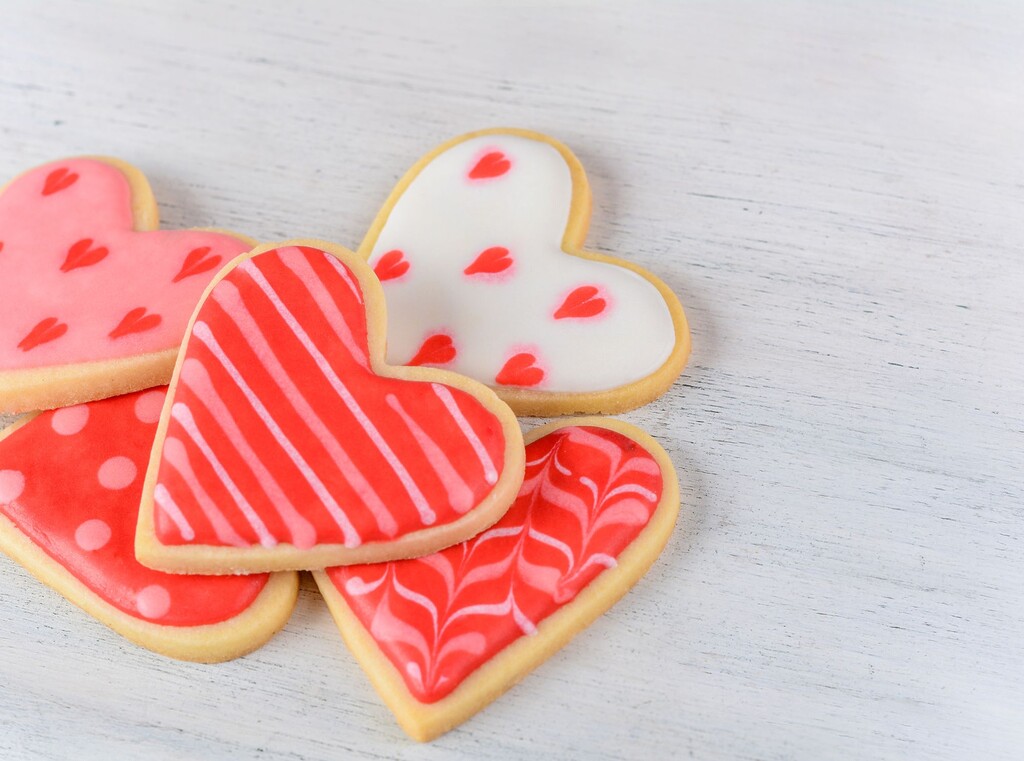 Hartvormige suikerkoekjes met roze en rode glazuurdecoratie.