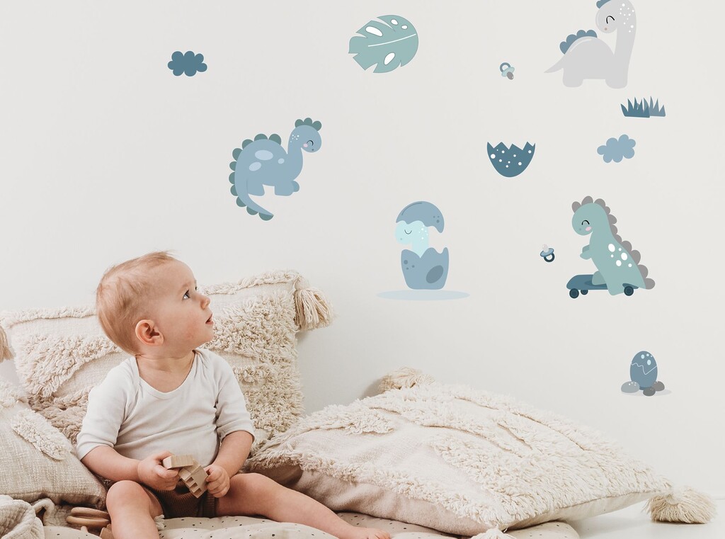 Baby zit op bed in een babykamer met blauwe dieren muurstickers