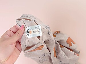 Close-up of a personalized name label with the name Noah applied to the care tag inside a child’s beige garment.