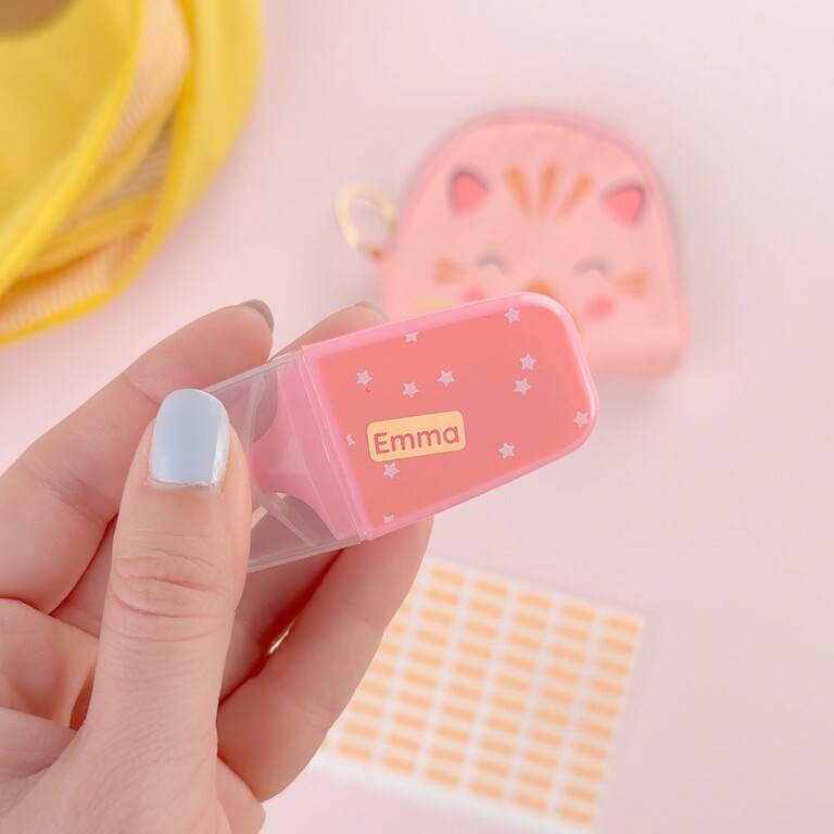 Hand holding a pink highlighter labeled with the name Emma, with mini name labels in the background