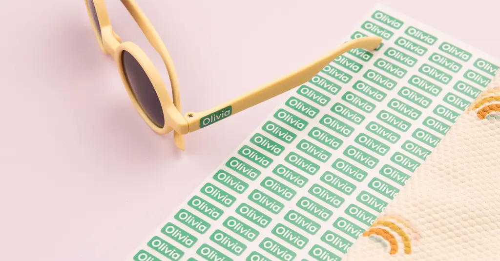 Groen mini-naamstickertje op gele zonnebril, met een bijpassend stickervel en zomeraccessoires