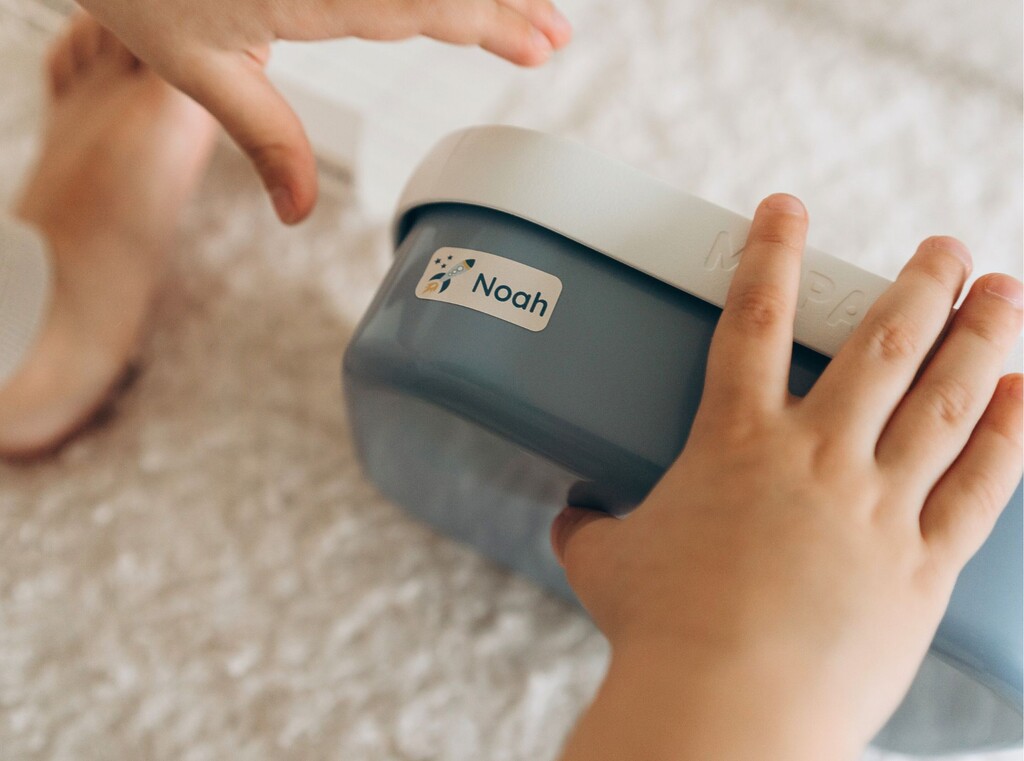 Kinderhanden houden een blauwe lunchbox met de naam noah erop gedrukt