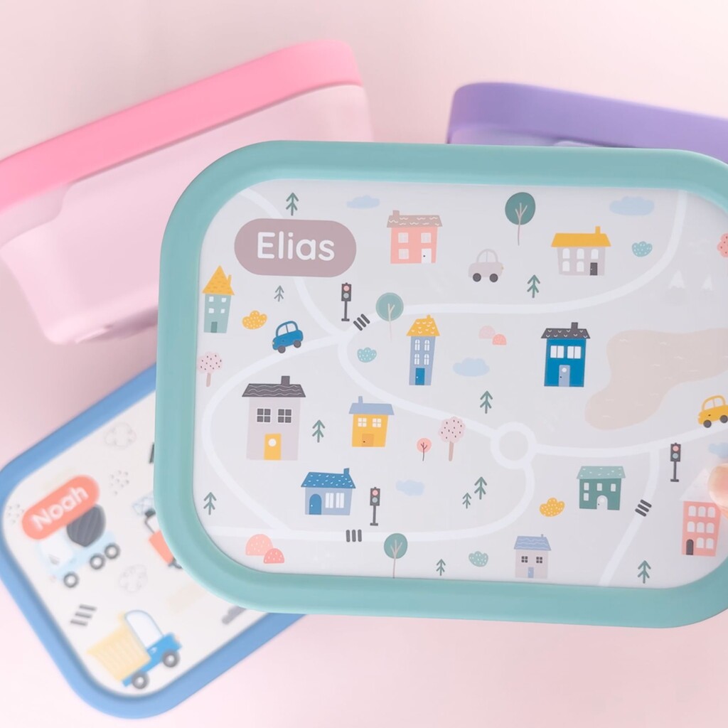 Colorful lunch boxes with playful city map design and personalized name on the lid