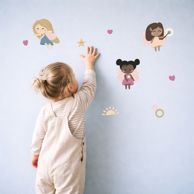 meisje plakt feeën-naamstickers op de muur