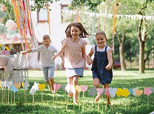 Kinderen rennen samen op een kinderfeestje buiten met ballonnen en versieringen