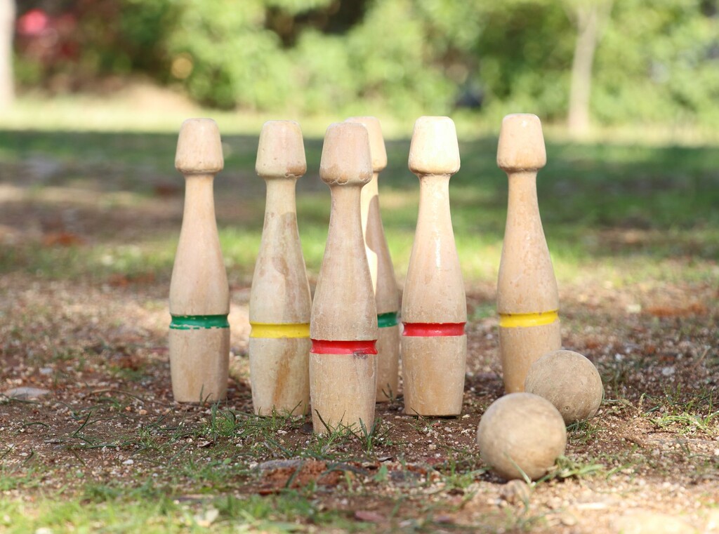 Houten kegels en houten ballen opgesteld voor een kegelspel in de buitenlucht
