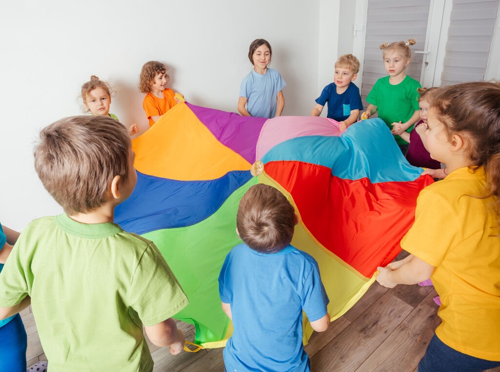Kinderen spelen samen met een kleurrijk speeldoek op een kinderfeestje