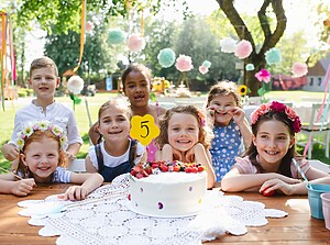 Kinderen zitten samen rond een verjaardagstaart op een kinderfeestje buiten
